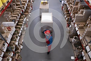 Man in hardhat working with pallet truck at warehouse, above view. Logistics center