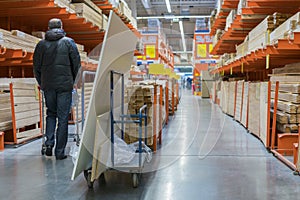 A man in a hardware store. Carts loaded with boards. shop of building materials. Racks with boards, wood and building material.