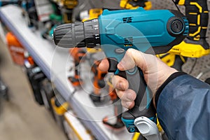 A man in a hardware store chooses a new drill or screwdriver. Screwdriver tool in hand closeup