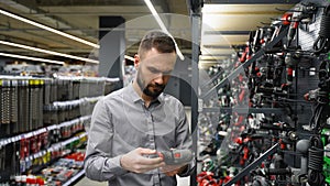 A man in a hardware store chooses a new screwdriver or drill