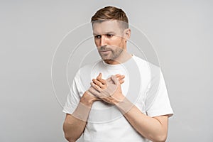Man has breathing problems, panic attack, suffocation holding hands on chest on gray background.
