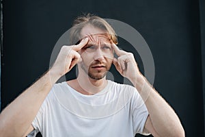 A man has a deep headache at dark wall