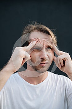 A man has a deep headache at dark wall