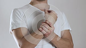 The man has a sore arm, pain in the arm. Close up. Isolated on a gray background
