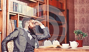 Man has terrible headache. Bearded man in formal suit suffers from negative thoughts and looks unsatisfaied. Mature man