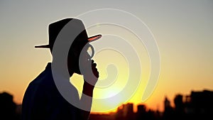 Man in hat as silhouette looking using magnifying glass