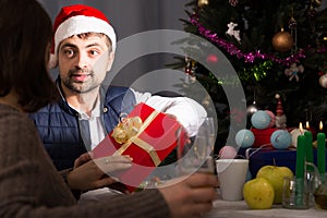 Man in hat giving present to woman at New Year dinner