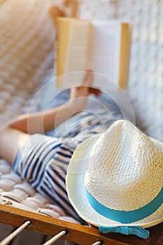 Man in hat in a hammock with book on a summer day