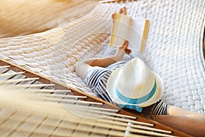 Man in hat in a hammock with book on a summer day