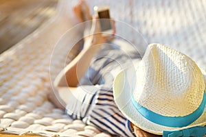 Man in hat in a hammock with mobile phone on a summer day