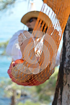 Man in hat in a hammock on pine tree in Crimea a summer day