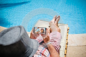 Man in a hat lying on a lounger with a smartphone