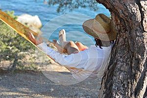 Man in hat relaxing in a hammock on pine tree in Crimea a summer day