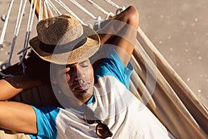 Man with hat sleeping in a hammock on the beach