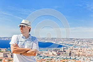 Man in a hat and sunglasses posing against the city of Marseille