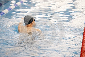 Man an in hat swimming in indoors swimming pool breaststroke photo