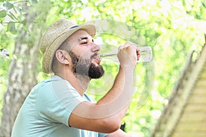 Man in hat and t-shirt drinks a drink from a bottle