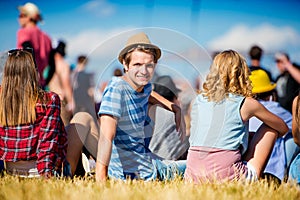 Muž s klobúkom, tínedžeri, letný festival, sediaci na tráve