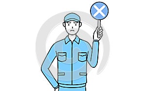 Man in hat and work clothes holding a placard with an X indicating incorrect answer