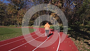 Man have sport exercises at race track. Male athlete running outdoors