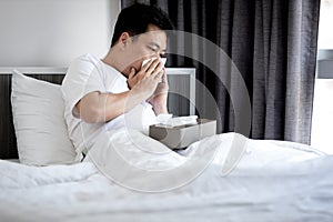 man have a stuffy nose,runny nose,blow or wipe one's nose with tissue paper,asian male have a fever and cold or flu, photo