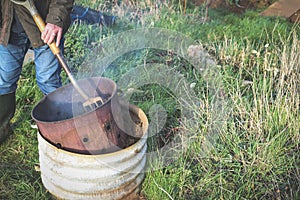 Man having a bonfire at an allotment or community garden vegetable plot to dispose of garden waste