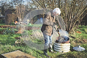 Man having a bonfire at an allotment or community garden vegetable plot to dispose of garden waste photo