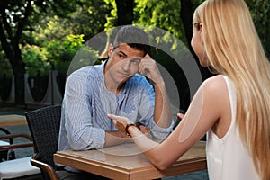 Man having boring date with talkative woman in outdoor cafe