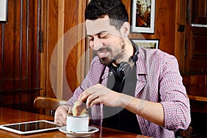 Man having breakfast with headphones and digital tablet.