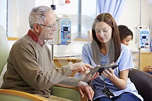 Man Having Chemotherapy With Nurse Using Digital Tablet