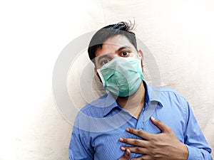 Man having chest pain difficulty in breathing wear face mask hands on chest