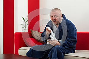 Man having a cold holding tissue with box full of tissues