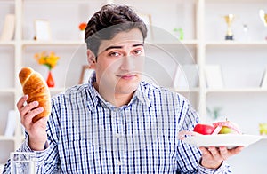 Man having dilemma between healthy food and bread in dieting con