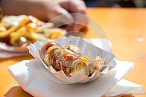 Man having German Currywurst sausage with curry sauce, French fries and mayonnaise on food market