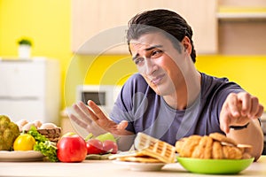 The man having hard choice between healthy and unhealthy food