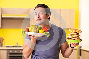 The man having hard choice between healthy and unhealthy food
