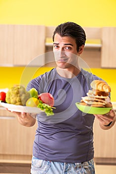 The man having hard choice between healthy and unhealthy food