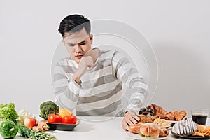 Man having hard choice between healthy and unhealthy food