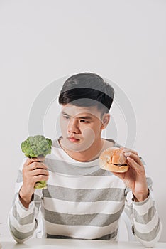 Man having hard choice between healthy and unhealthy food