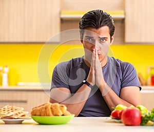 Man having hard choice between healthy and unhealthy food