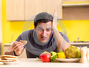 Man having hard choice between healthy and unhealthy food