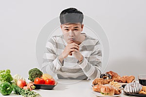 Man having hard choice between healthy and unhealthy food