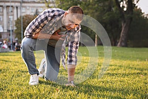 Man having heart attack on green grass in park