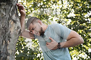 Man having heart attack near tree in park