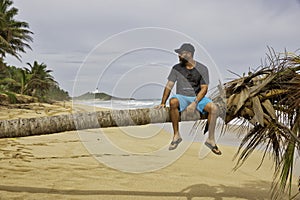 Man having a leisure time relaxing on a palm tree