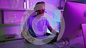 Man having live stream in neon room. Joyful gamer commenting actions in headset