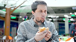 Man having lunch with hamburger in shopping mall.