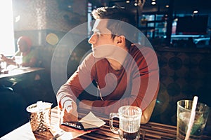 Man having morning breakfast with coffee in diner cafe and using his mobile phone.