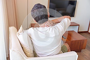 Man having Neck and Shoulder pain during sitting on sofa. due to fibromyalgia, rheumatism, Scapular pain, office syndrome and