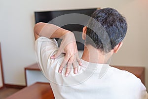Man having Neck and Shoulder pain during sitting on sofa. due to fibromyalgia, rheumatism, Scapular pain, office syndrome and